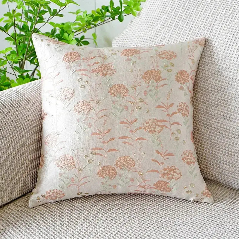 A jacquard floral pillow cover with a delicate peach and green pattern on cream featuring metallic threads