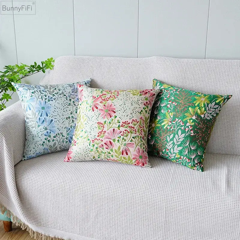 Three jacquard floral pillow covers in pink and green hues on a textured white sofa for bedroom decor