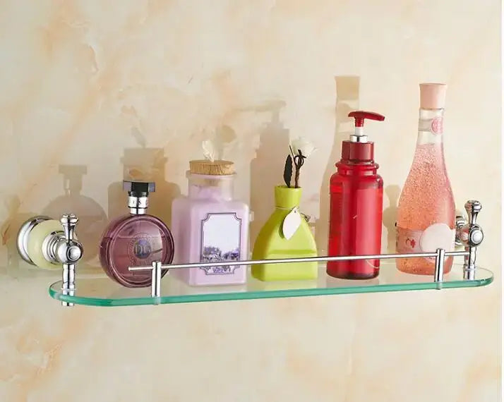 Clear glass shelf with chrome-finished metal brackets holding colorful bottles in jade bathroom set chrome accessories by decorbites brass