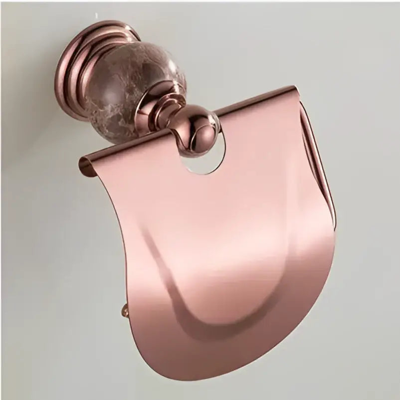 Rose gold metallic toilet paper holder with polished curved design and decorative spherical top in jade rose gold bathroom set