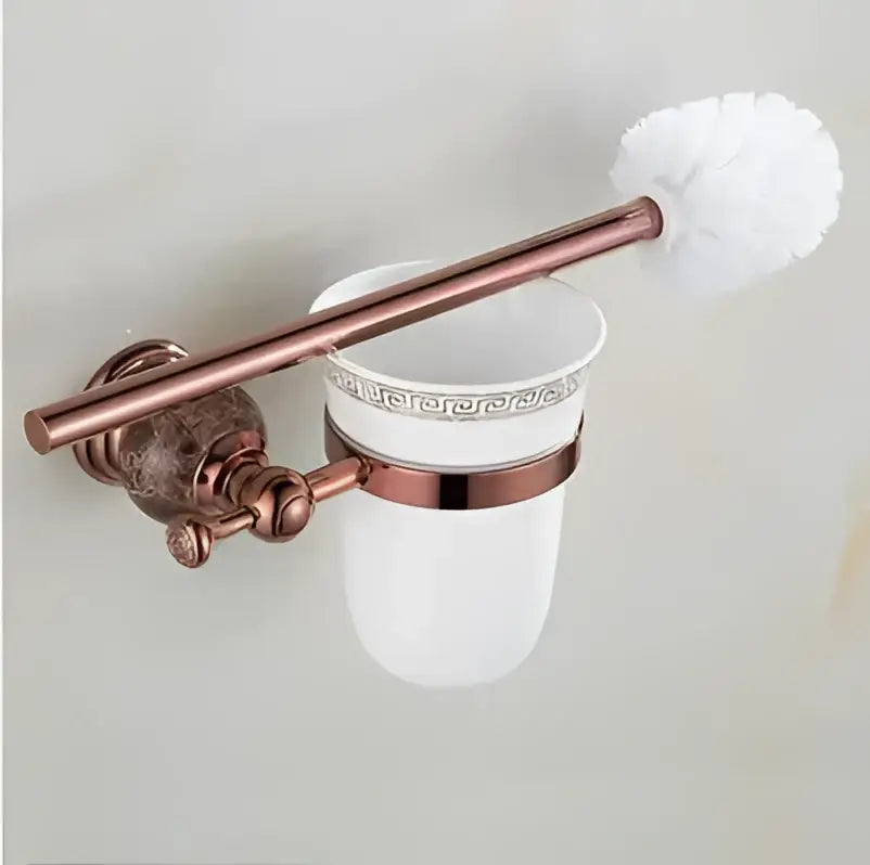 Copper-finished toilet brush holder with a white ceramic cup featuring silver greek key pattern in jade rose gold bathroom set