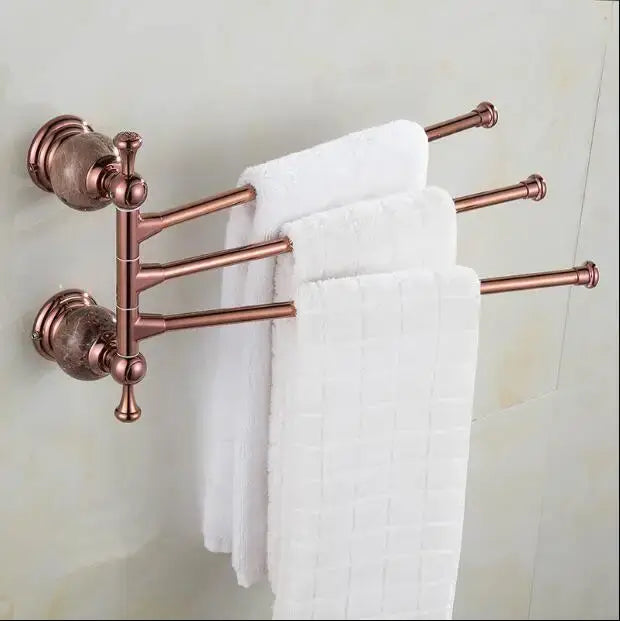 Copper-finished wall-mounted towel rack with four extendable arms holding white towels in jade rose gold bathroom set