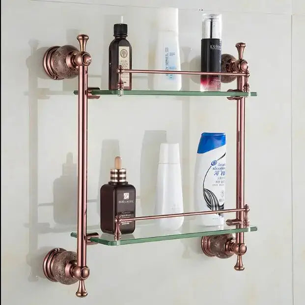 Antique brass double-tiered glass shelf with ornate turned-post brackets in a jade rose gold bathroom set