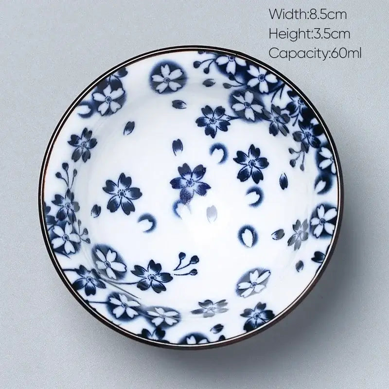 A delicate white decorbites ceramic kung fu tea porcelain bowl with blue cherry blossom patterns and a dark rim