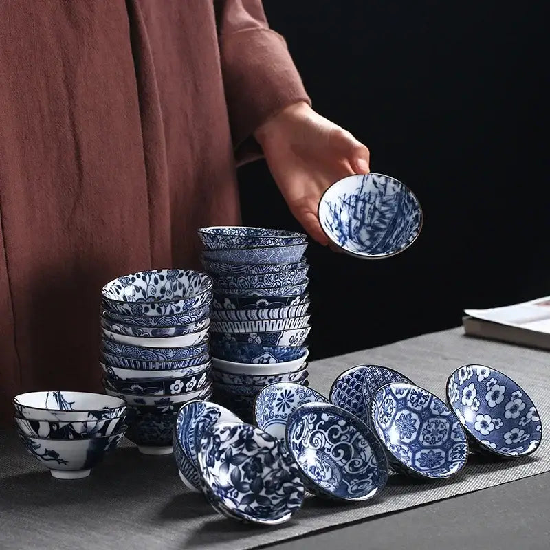 A hand holds a blue and white decorbites ceramic kung fu tea porcelain bowl with intricate bamboo and floral patterns