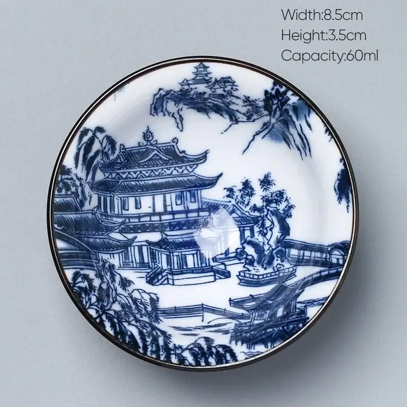 A delicate white porcelain kung fu tea cup with blue hand-painted chinese landscapes and a metallic rim by decorbites ceramic