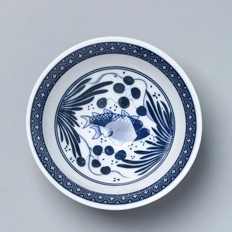 A white ceramic kung fu tea cup porcelain bowl with blue and black fish and aquatic plant design from decorbites ceramic