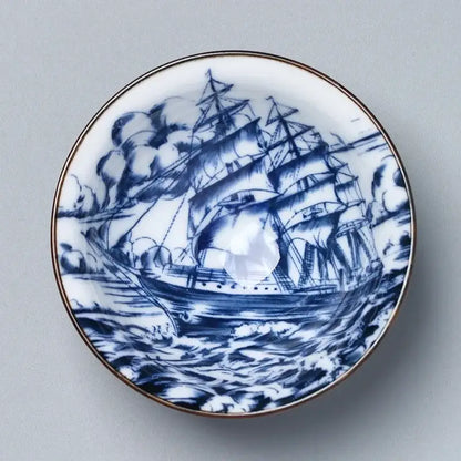A white ceramic kung fu tea saucer with a blue hand-painted sailing ship and gold rim by decorbites ceramic