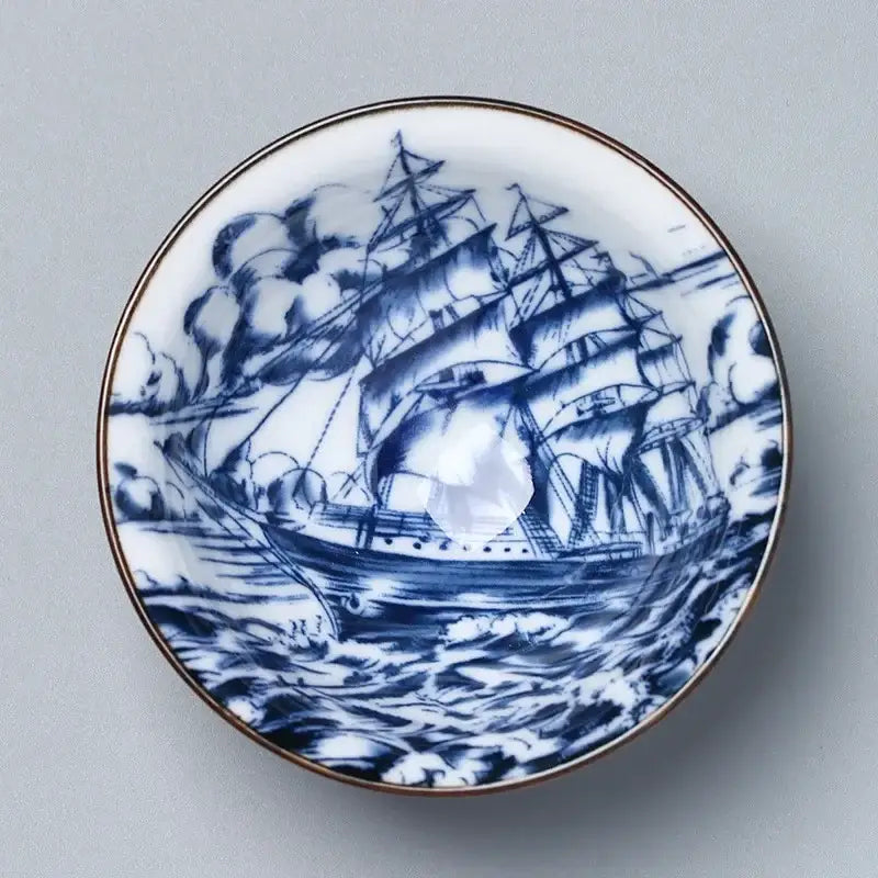 A white ceramic kung fu tea saucer with a blue hand-painted sailing ship and gold rim by decorbites ceramic
