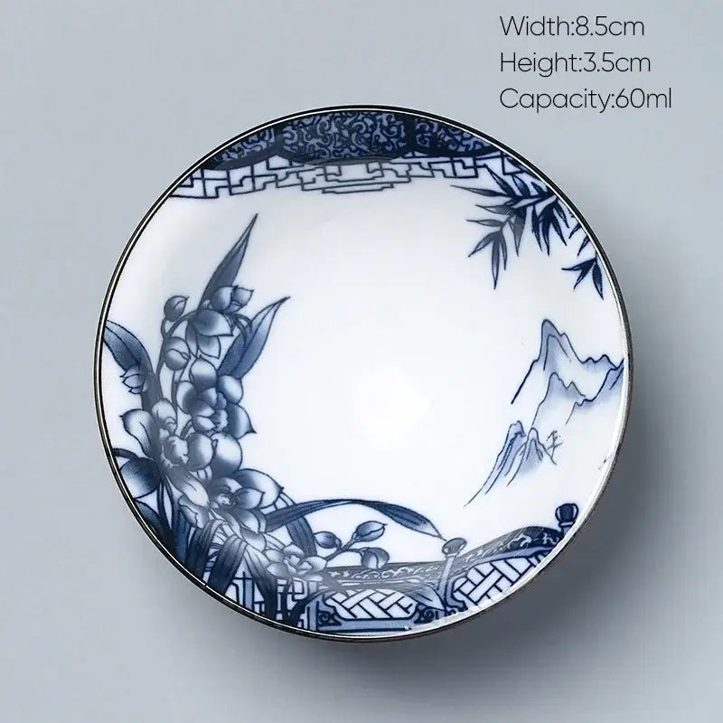 A delicate white porcelain decorbites ceramic kung fu tea cup with intricate blue hand-painted flowers and mountains