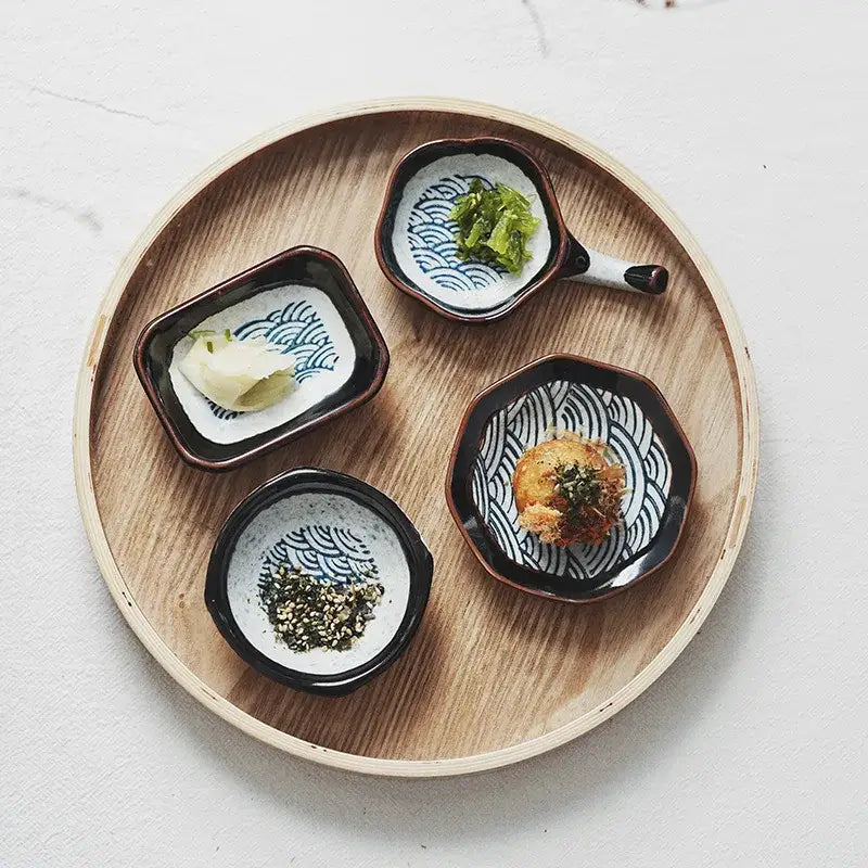 Set of four ceramic japanese porcelain dipping bowls with black rims and blue wave patterns for sauce serving