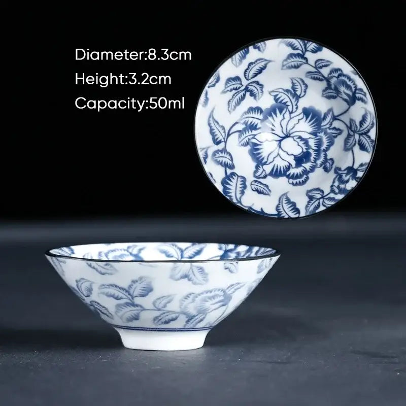 A delicate white ceramic kung fu tea cup with intricate blue floral patterns and matching lid in traditional porcelain style
