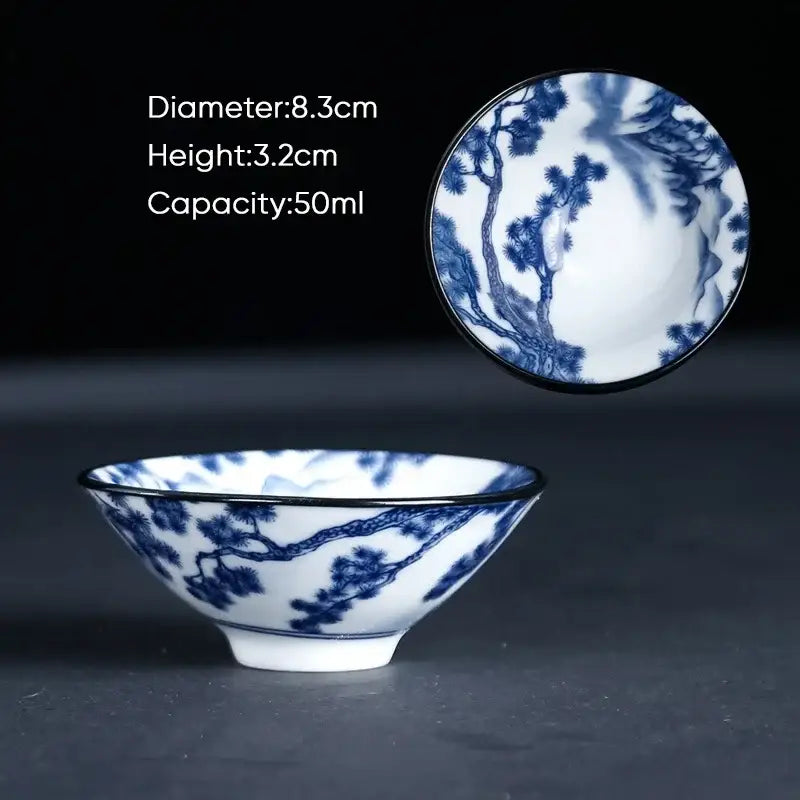 A delicate blue and white ceramic kung fu tea cup with intricate pine tree designs and a black rim porcelain finish