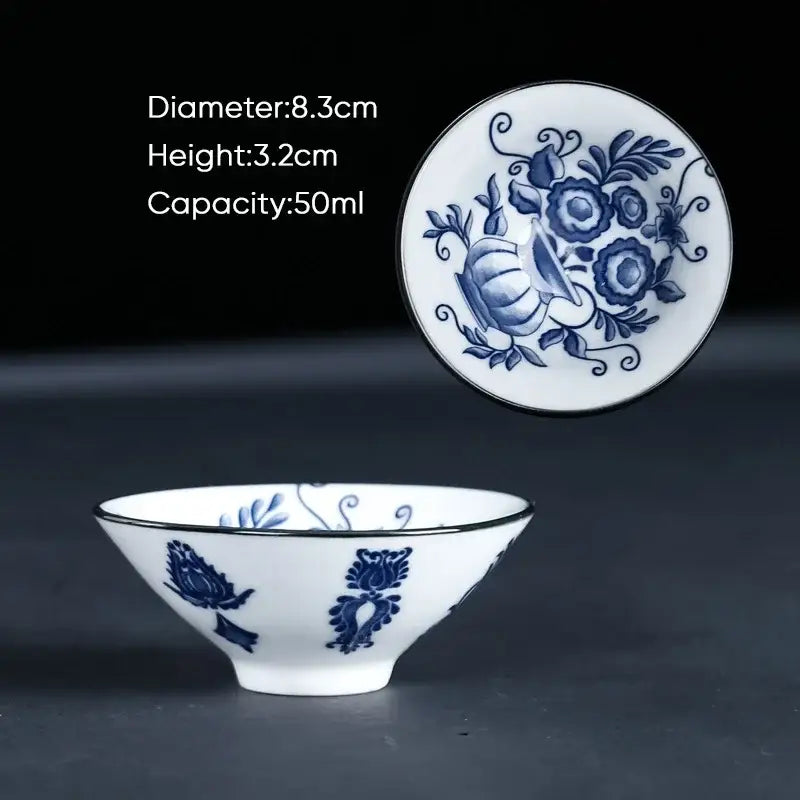 A delicate white ceramic kung fu tea cup with blue floral patterns and a black rim for dining room use