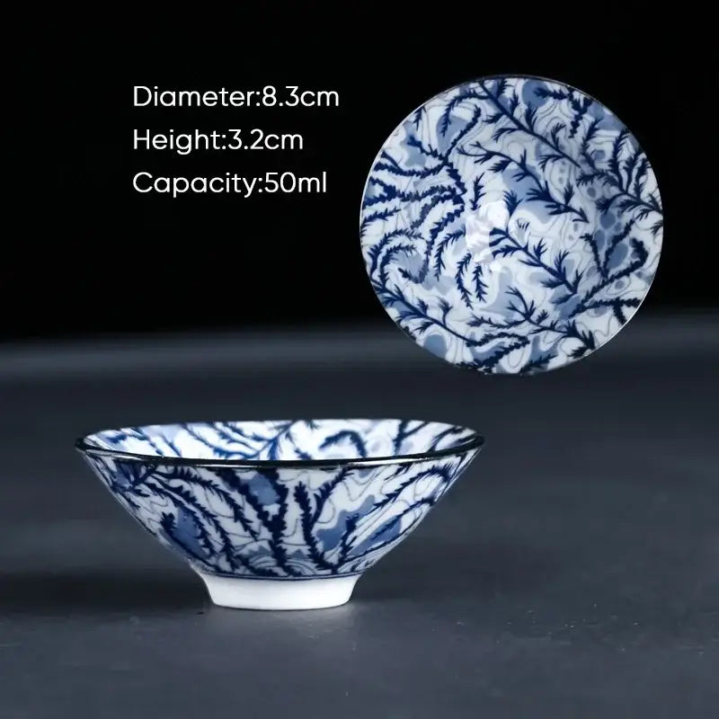 A delicate blue and white ceramic kung fu tea cup with an intricate hand painted botanical leaf design