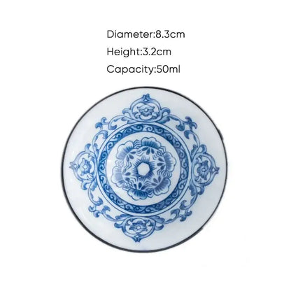 A delicate white ceramic kung fu tea saucer with blue floral scrollwork and a black rim for porcelain tea cup set