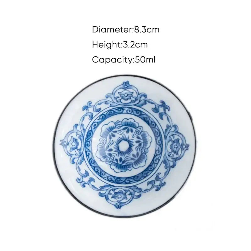 A delicate white ceramic kung fu tea saucer with blue floral scrollwork and a black rim for porcelain tea cup set