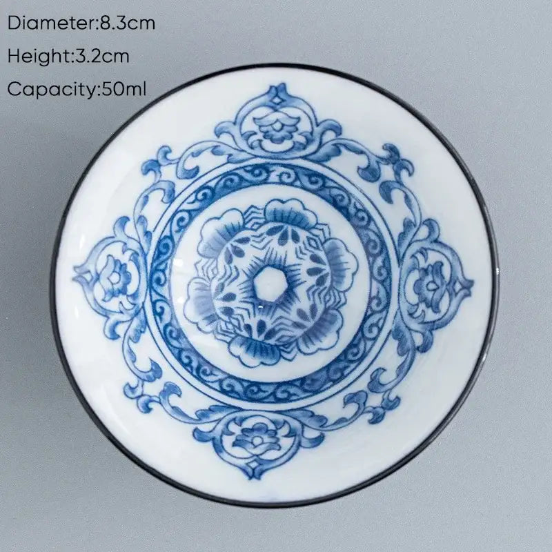 A white ceramic kung fu tea cup with intricate blue floral patterns and a black rim for dining room use