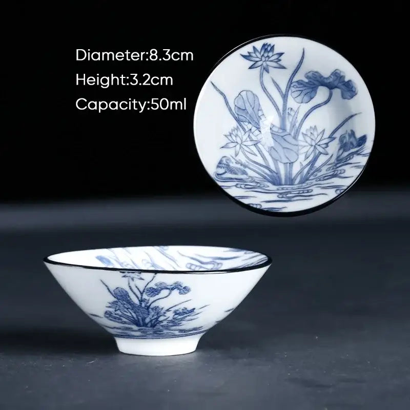A delicate white porcelain ceramic kung fu tea cup with intricate blue lotus designs and a black rim for dining room use
