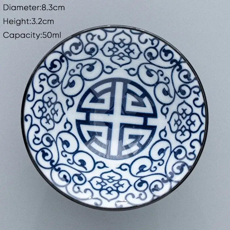 A white ceramic kung fu tea cup with intricate blue floral patterns and a central shou character design