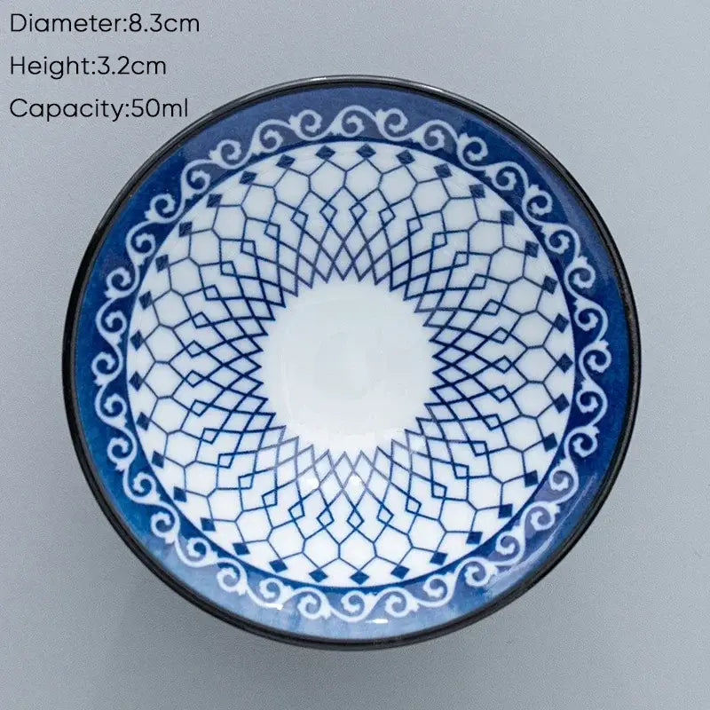A blue and white ceramic kung fu tea cup with geometric lattice pattern and ornate scrollwork border for dining room use