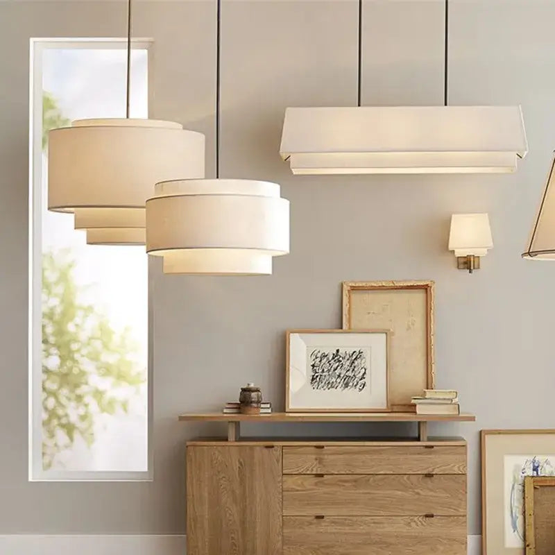Modern beige tiered pendant lamp with cream fabric shades and black cords above wooden console by decorbites camden japanese