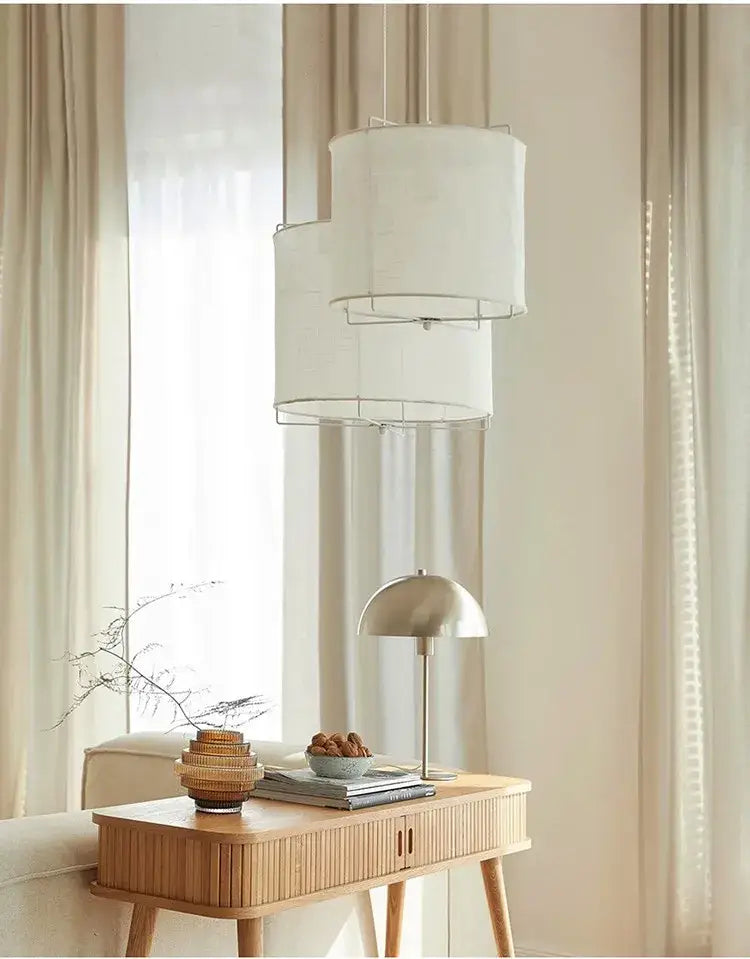 Modern tiered linen fabric chandelier with white decorbites linen fabric shades hangs above wooden console table