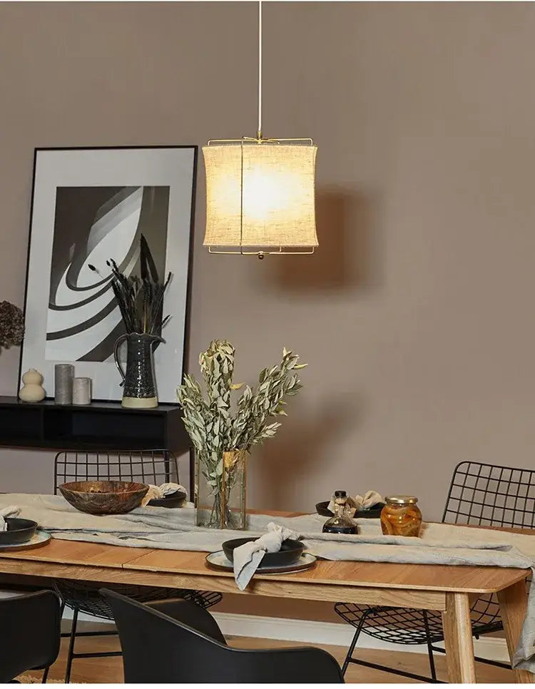 A warm-toned rectangular decorbites linen fabric chandelier with a gold frame hangs above the dining table