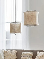 Two beige decorbites linen fabric chandelier pendant lamps with black metal frames hang from the ceiling in a bedroom