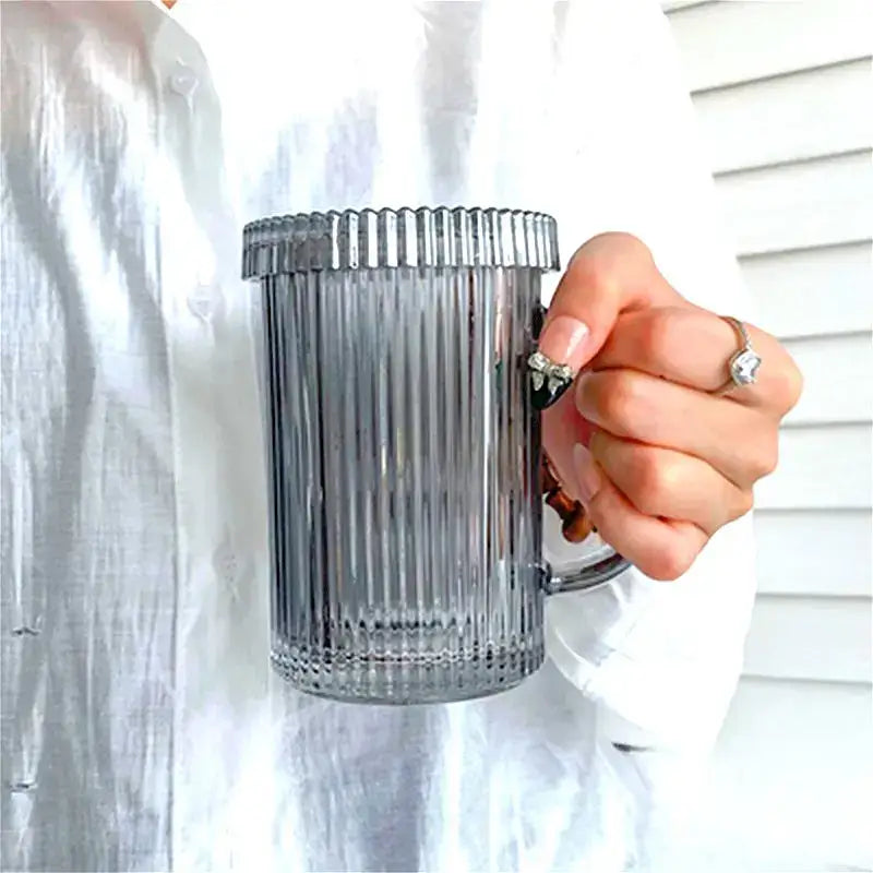 A translucent gray ribbed glass coffee cup from decorbites glass coffee cup set held by a hand with rings