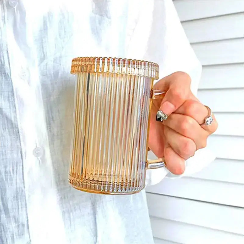 A translucent amber glass coffee cup with vertical ridges and handle held in hand from a Japanese ribbed glass coffee cup set