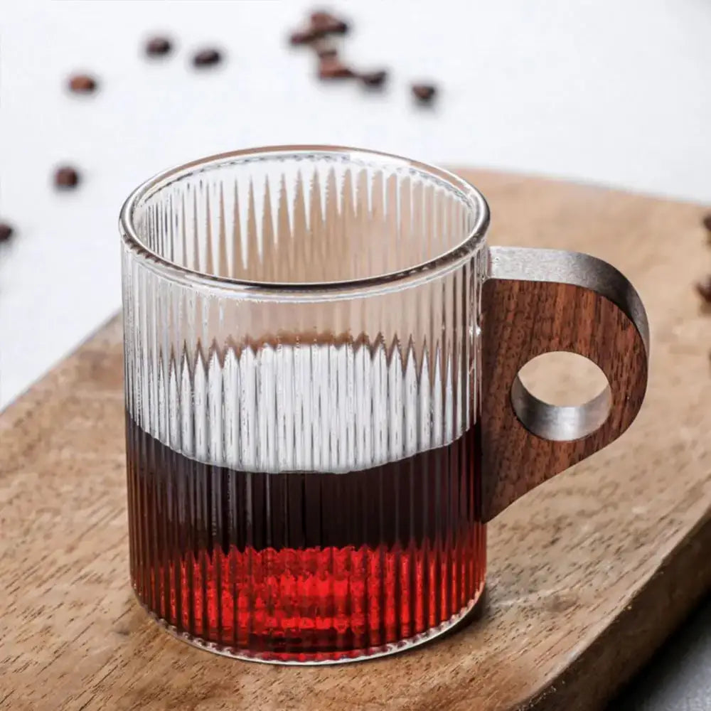 Japanese ribbed glass coffee mug with wooden handle and vertical ridges filled with layered coffee and red liquid