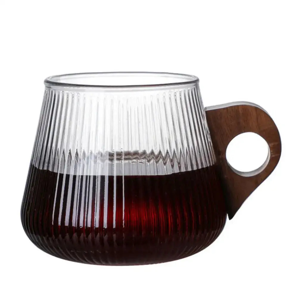 Japanese ribbed glass coffee mug with vertical texture and dark wood handle filled halfway with rich red liquid