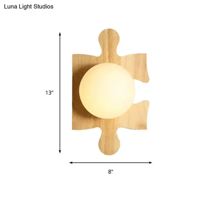 A warm beige wall light with a softly glowing spherical fixture mounted on a natural wooden puzzle base