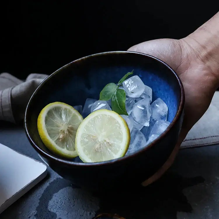 A deep blue ceramic salad bowl with a dark rim holds ice lemon slices and basil in a decorbites salad bowl set