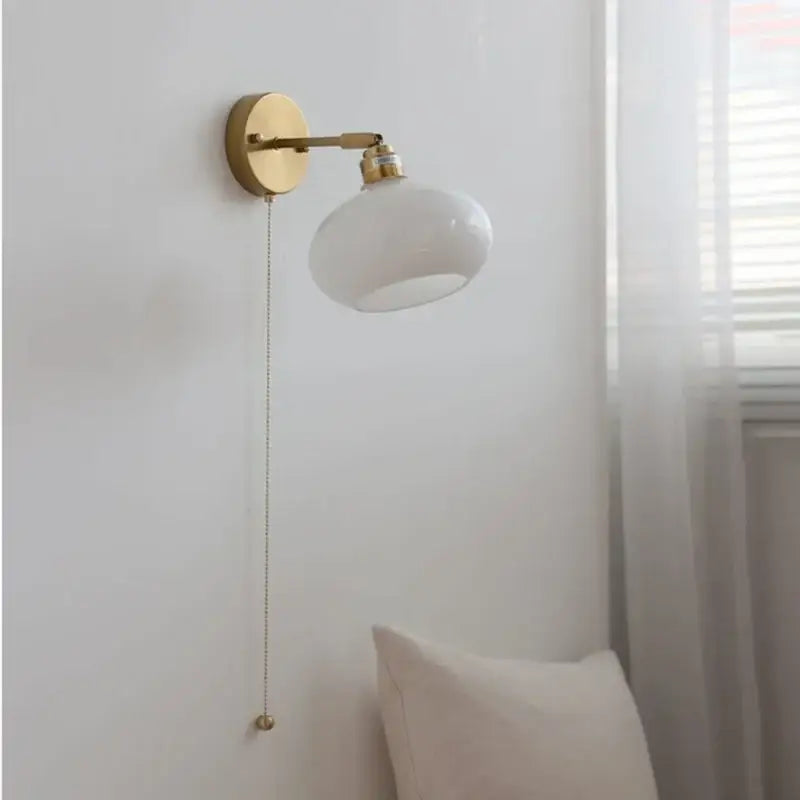 A sleek white glass globe wall sconce with brass finish and pull chain decorbites japanese style led bedroom light