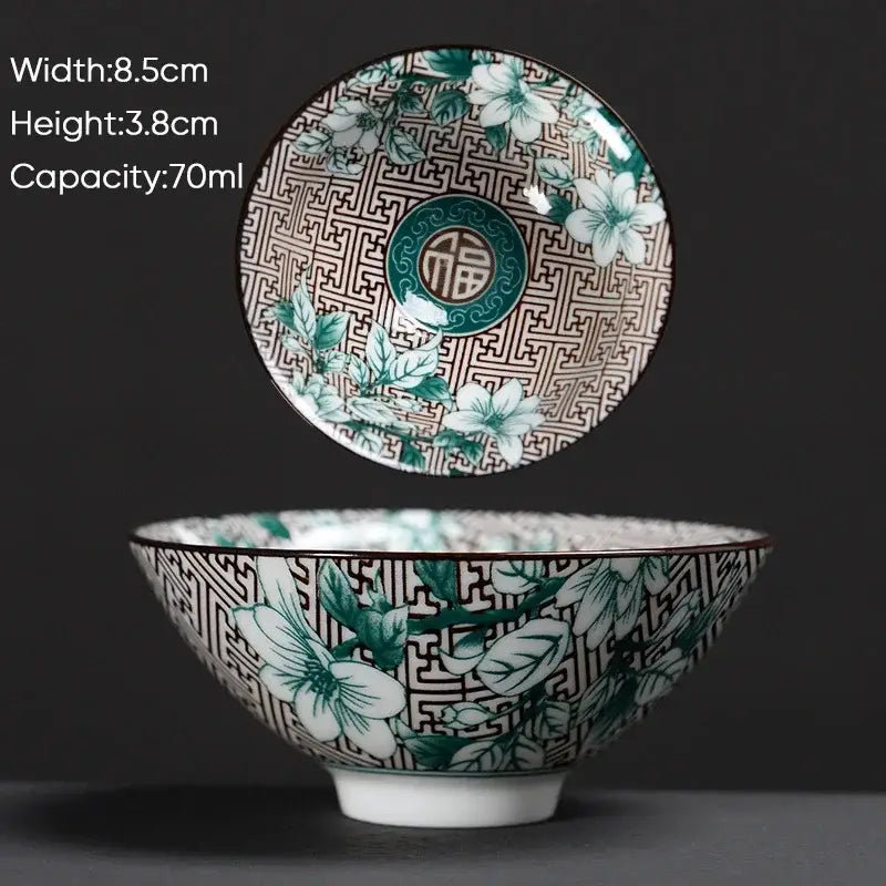 A white ceramic kung fu tea cup with green and black floral patterns and geometric lattice decorbites blue design
