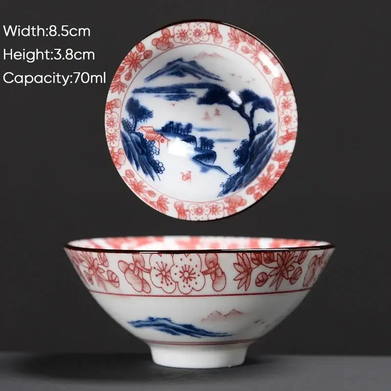 A delicate white ceramic kung fu tea cup with blue and red hand-painted cherry blossom landscape decorbites blue design