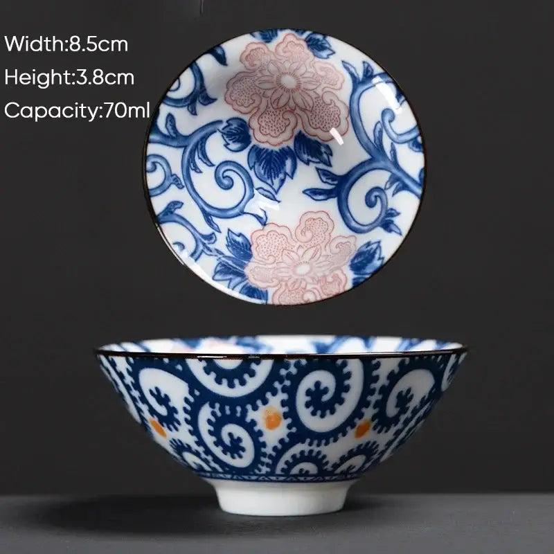 A delicate white ceramic kung fu tea cup with blue and pink floral patterns and orange dot accents for decorbites blue set
