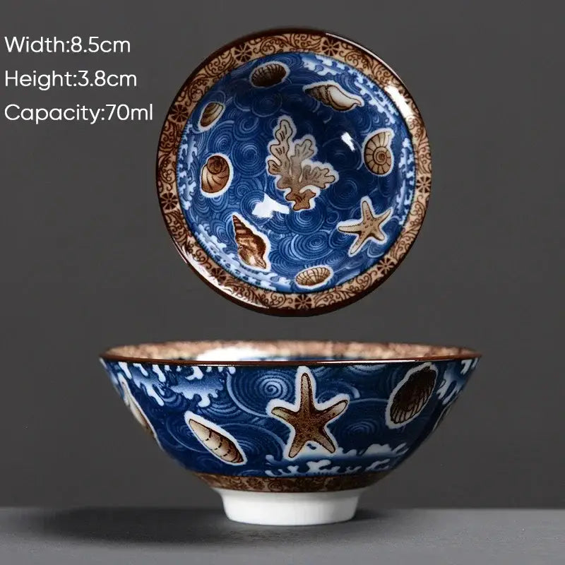 A blue ceramic kung fu tea cup with brown rim and white wave seashell decorbites blue multi color design