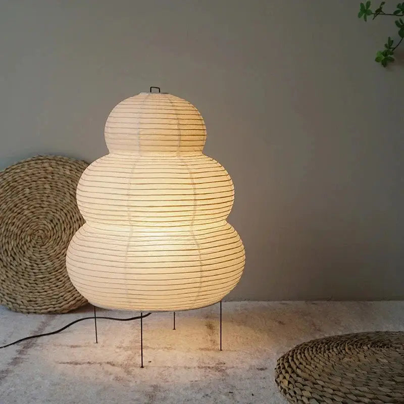 A warm glowing Japanese style rice paper desk lamp with three-tiered rounded design and subtle vertical ridges