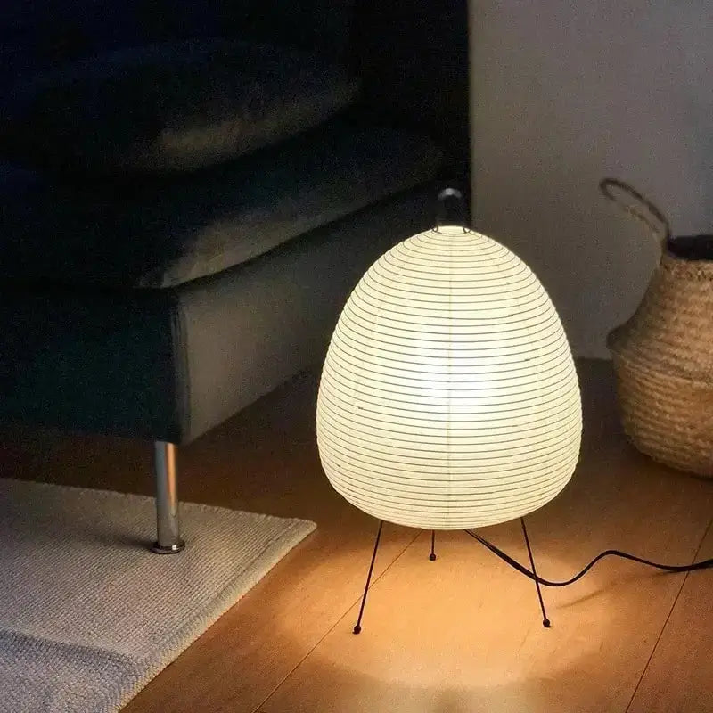 Warmly glowing japanese style rice paper table lamp with white paper lantern body and black metal legs for bedroom decorbites