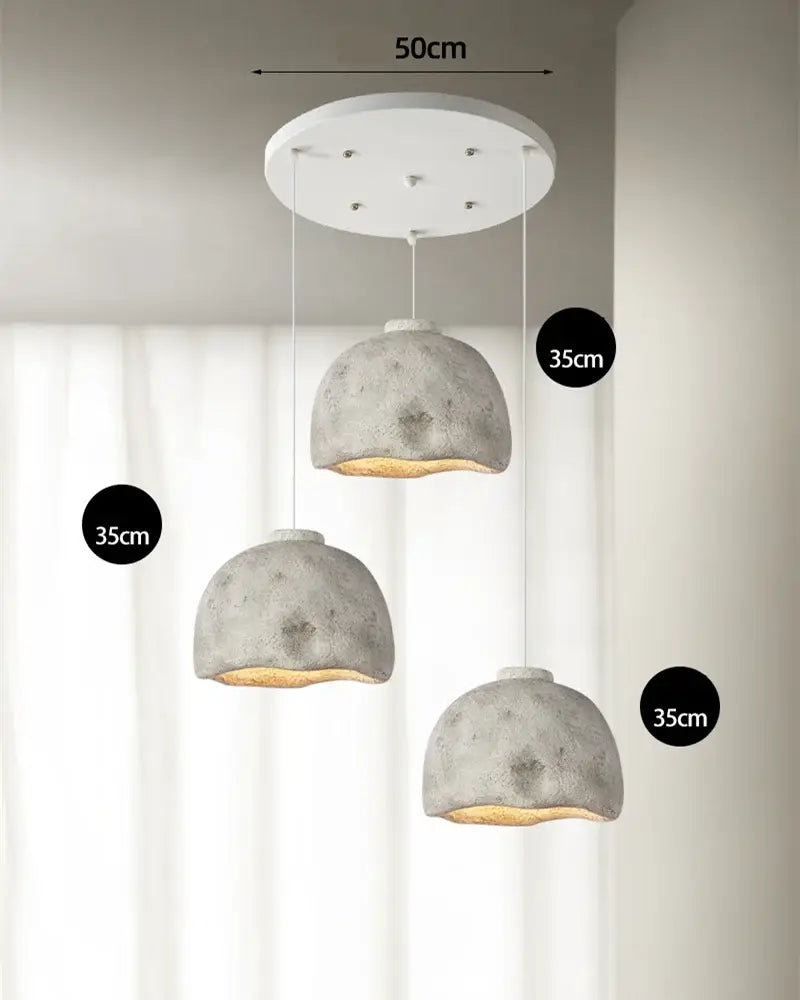 Set of three gray concrete resin pendant lights with a white circular ceiling mount for dining room use