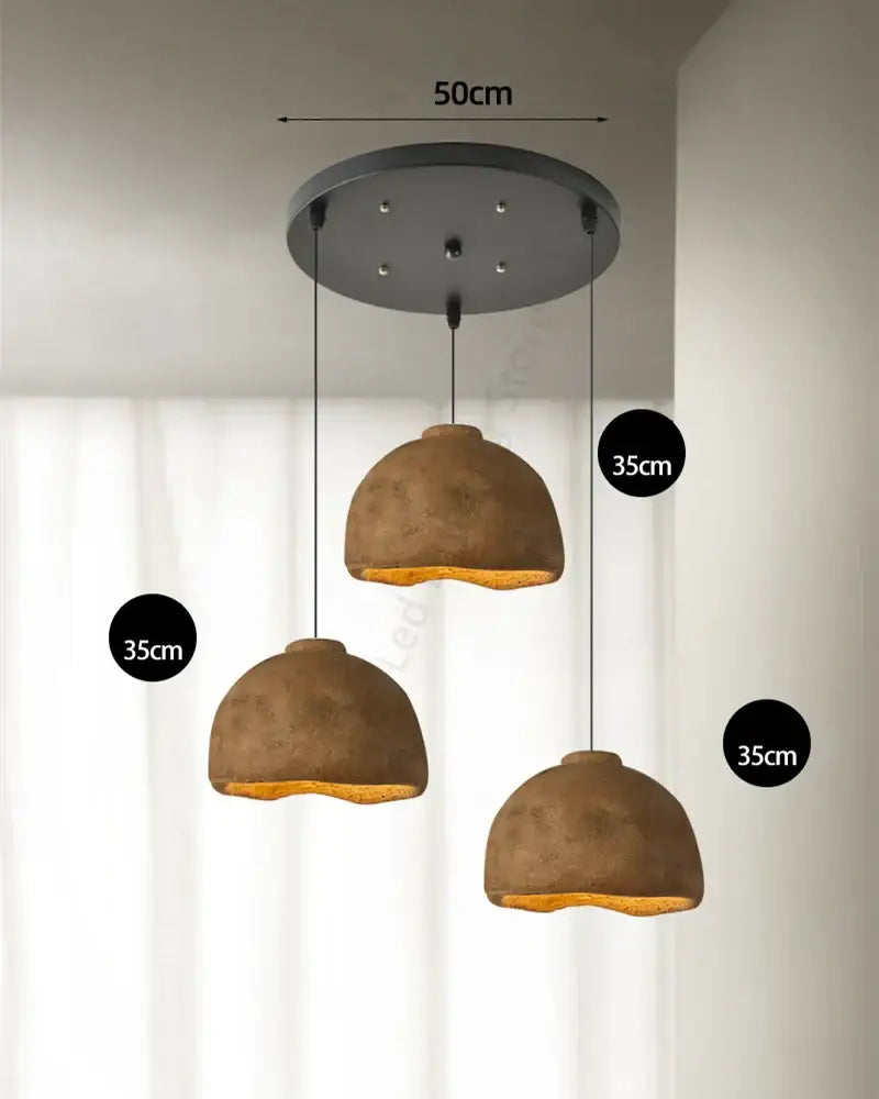 Three rustic brown resin pendant lights with concrete dome shades hang from a black ceiling mount for dining room use