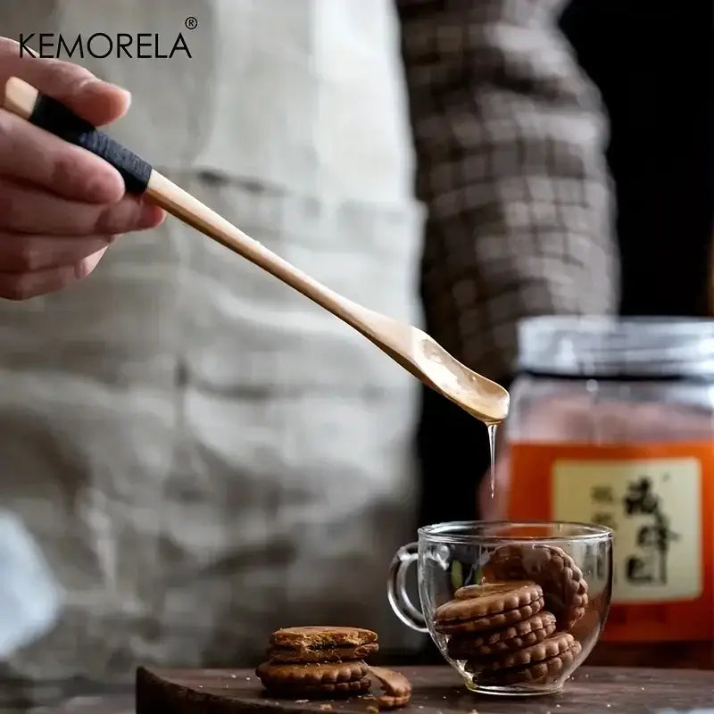 A sleek japanese style wooden spoon set natural and dark wood with a black handle dripping honey over chocolate cookies