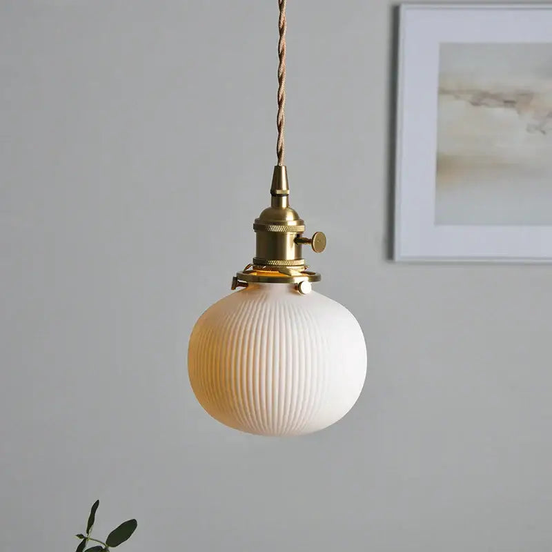 Vintage-style pendant light with frosted white ribbed glass globe and polished copper finish brass hardware