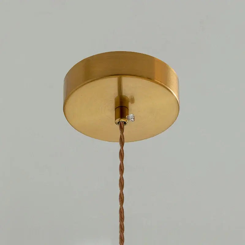 Japanese white fluted ceramic pendant light with gold circular ceiling fixture and twisted copper cable with polished copper finish