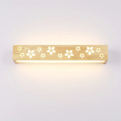Japanese wooden floral wall lamp with natural wood finish and delicate cutouts emitting warm glow for bedroom use