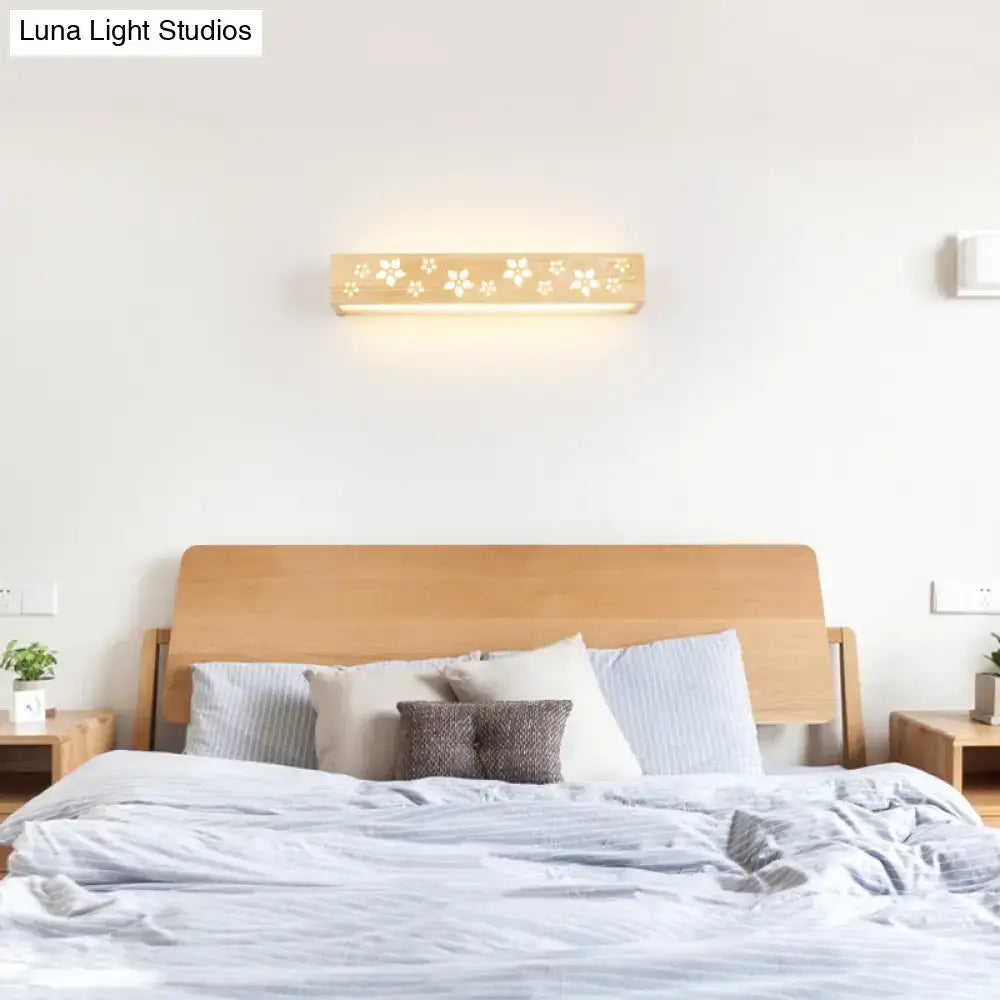 A warm-toned Japanese wooden floral wall lamp with shelf featuring delicate cutouts and sleek rectangular design
