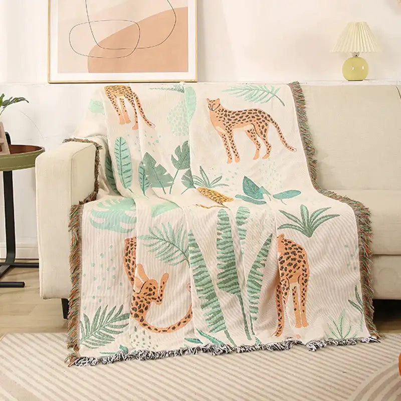 Cozy cream-colored leopard print throw blanket with orange cheetahs and green leaves, fringed edges for decorbites leopard print decor